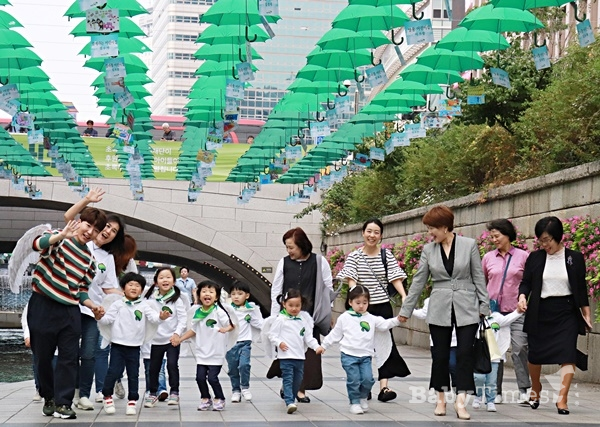 새문안 어린이집 아동들과 도티가 초록우산이 전시되고 있는 청계광장에서 기념촬영을 하고 있다.