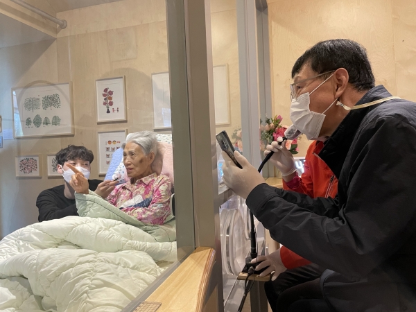 시립동부노인요양센터 ‘가족의 거실’에서 한 가족이 유리창을 사이에 두고 비접촉 대면 면회를 진행하고 있다. (사진=서울시 제공)