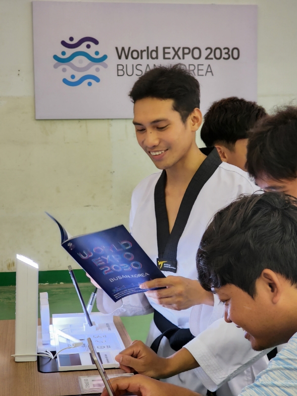 대회에 참가한 캄보디아 청소년 선수들이 스마트폰, TV 등 삼성전자 제품을 체험하고 부산엑스포 안내 책자를 살펴보고 있다. (사진=삼성전자 제공)